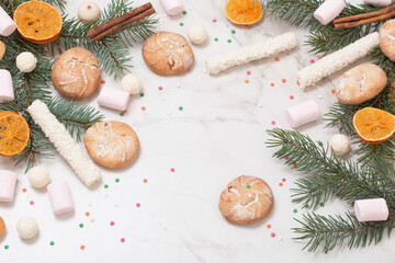 candies and cookies with christmas tree branches on white marble background