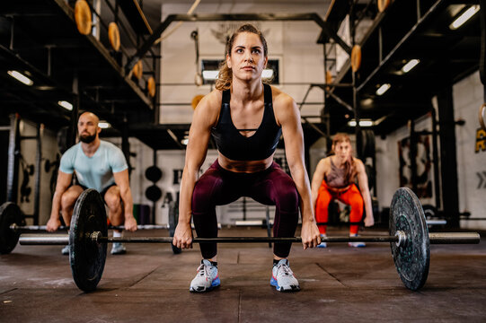 Group of multiethnic sports strong people make sport exercise with barbell.