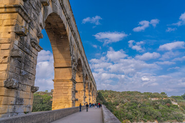 Aqueduct arch with back view of people at Pont du Gard three-tiered aqueduct