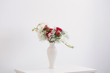 red and white bouquet in vase on white background