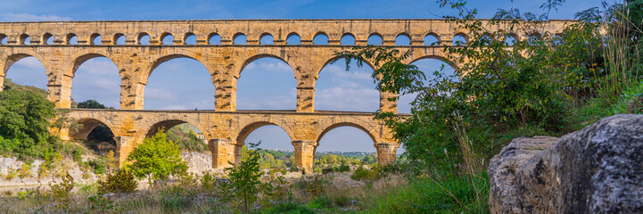 Fototapeta na wymiar Panorama view to the limestone Pont du Gard three-tiered aqueduct at the river Gardon.
