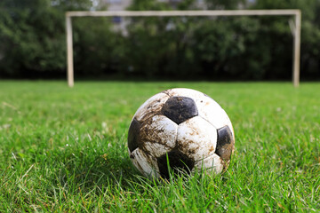 Dirty soccer ball on green grass outdoors