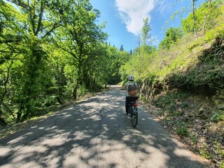 Cycling is awesome: beautiful day with blue sky in tuscany, italy. young sport woman rides her ebike