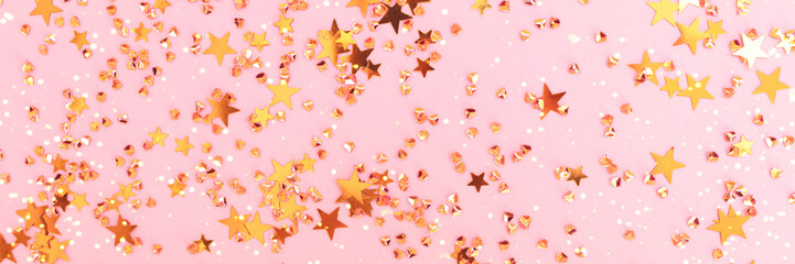 Banner with shiny gold colored stars and crystals confetti on a pink background. Festive texture. Selective focus.