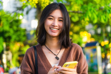 Pretty young asian female with big smile and stand Outdoor. She having fun taking light cheerful...