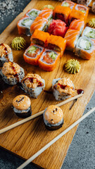 A closeup of set of sushi rolls with chopsticks on the wooden board, party food. Fresh food..
