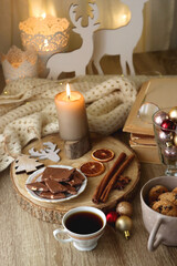 Cup of tea or coffee, various sweets and spices, Christmas decorations, comfy blanket, books and glasses. Selective focus.