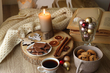 Cup of tea or coffee, various sweets and spices, Christmas decorations, comfy blanket, books and glasses. Selective focus.