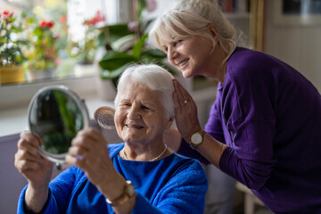 Woman combing hair of elderly mother 
