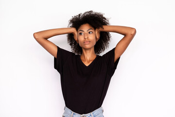 Portrait of ignorant young woman covering ears with hands over white background. African American...