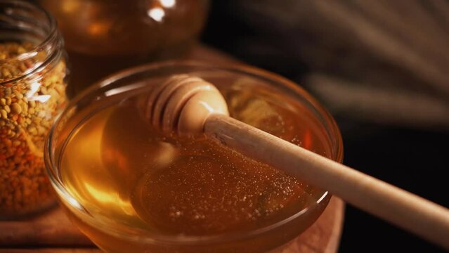 Honey pouring in glass bowl on black background Close up