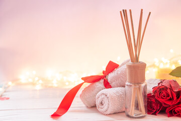 Spa composition for Valentine's Day with incense sticks, towel and red roses.
