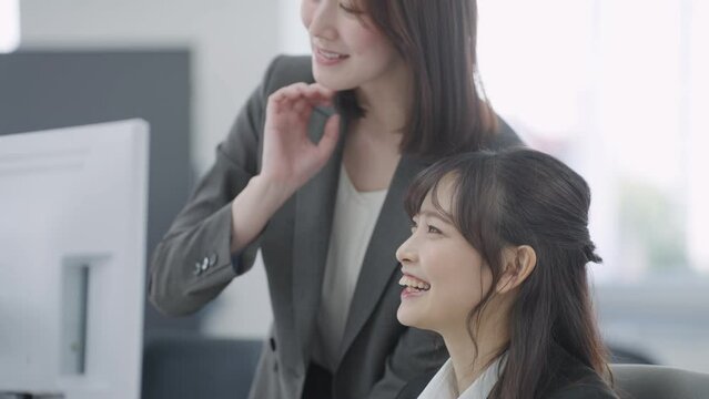 パソコンを見て話すビジネスウーマン（パソコン・チェック・確認・会話）