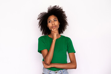 Fototapeta na wymiar Portrait of pensive young woman touching chin over white background. African American lady wearing green T-shirt and jeans looking away with thoughtful expression. Thinking or planning concept
