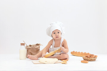 Happy cute asian child in apron prepares pastry from dough.