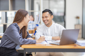 Obraz premium Two Asian business colleagues working together on new project in workplace office.