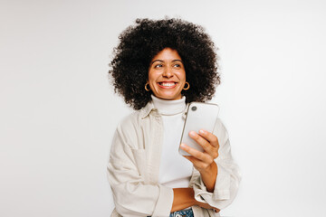 Thoughtful young woman holding a smartphone in a studio