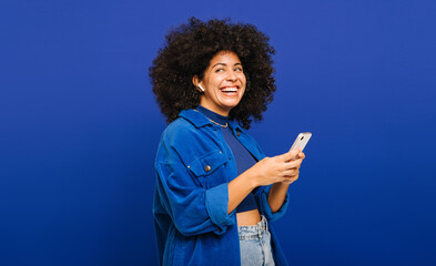 Woman with curly hair enjoying some music on her smartphone