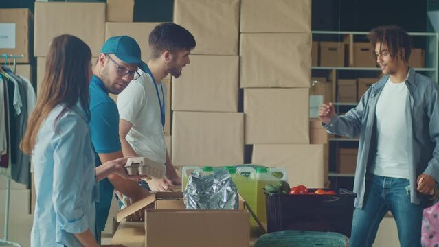 Friendly Volunteer Giving Donation Box With Food to Man and His Son at Distribution or Refugee Assistance Center. The Concept of Social Aid. Internally Displaced Persons