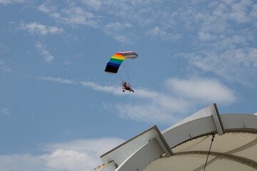Low-angle of a person flying with parachute cloudy sunlit sky background