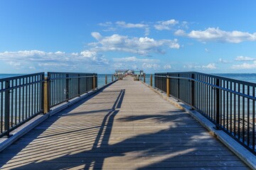 Long pier leading to the ocean at Holmes beach on a warm sunny day in Anna Maria island Florida