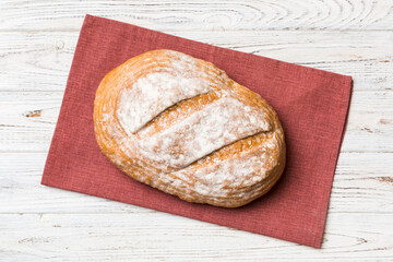 Freshly baked delicious french bread with napkin on rustic table top view. Healthy white bread loaf