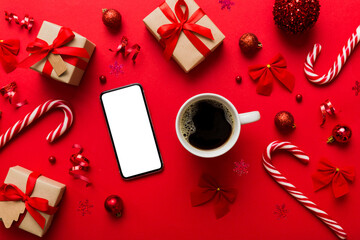 top view of smart phone with hot cup of coffee. Christmas decoration on colored background