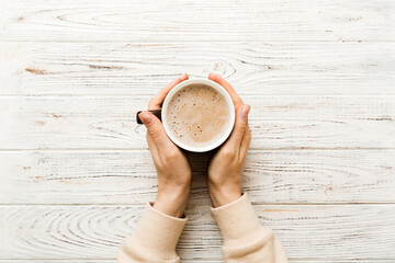 Minimalistic style woman hand holding a cup of coffee on Colored background. Flat lay, top view cappuccino cup. Empty place for text, copy space. Coffee addiction. Top view, flat lay