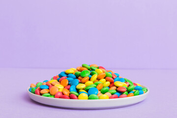 Multicolored candies in a bowl on a colored background. birthday and holiday concept. Top view with copy space