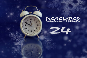 Calendar for December 24: white alarm clock on a blue background with bokeh, reflection from objects, name of the month december, numbers 24