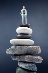 miniature people. the figure of a man stands on top of the stones. concept of achievements in life and success in business.