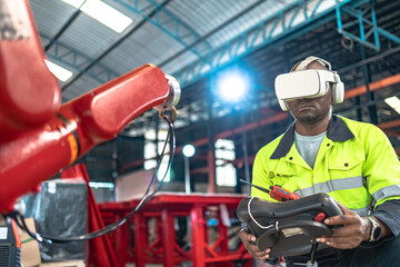 African American factory worker working with adept robotic arm in a workshop . Industry robot programming software for automated manufacturing technology .