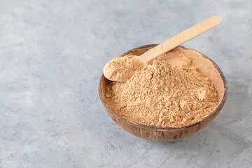 Maca root powder - a small bowl with a spoon on neutral background with space for text