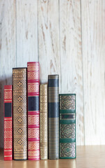 antique book spines in different colours and with gilt decorations. copy space. vertical image. selective focus.