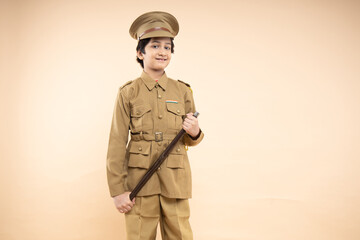 Young elementary indian boy kid wearing police uniform showing with his nightstick in hand isolated...
