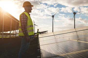 People working for solar panels and wind turbines - Renewable energy concept - Soft focus on man face © DisobeyArt