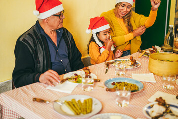 Happy latin family celebrating together during Christmas dinner - Focus on little girl face