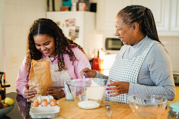 African mother and daughter preparing fruit cake at home - Focus on girl hands holding bag