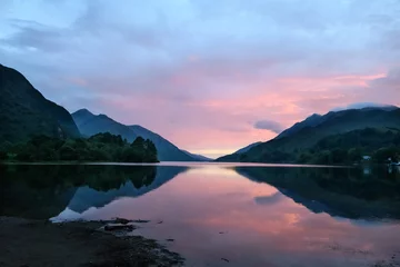 Foto op Plexiglas Kleurrijke zonsondergang in de Schotse Hooglanden met bergen, huizen, lucht en licht weerspiegeld in het meer © Simon