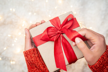 Close-up, gift box with red ribbons in female hands, top view.