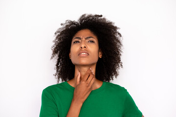 Fototapeta na wymiar Close-up of ill young woman touching sore throat over white background. African American lady wearing green T-shirt suffering from angina. Pulmonary diseases concept