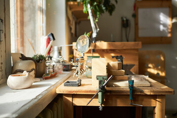 Background image of jewelers workstation with wooden table lit by sunlight in studio, copy space - obrazy, fototapety, plakaty