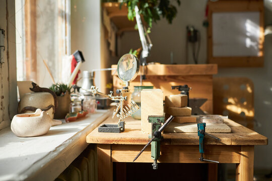Background image of jewelers workstation with wooden table lit by sunlight in studio, copy space - Powered by Adobe