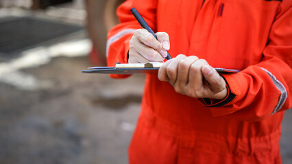 A safety officer is writing on the checklsit document during safety audit workplace at the factory....