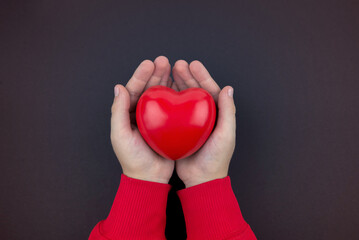 Top view photo of hands holding red heart on black background, healthcare, love, organ donation,...