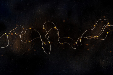 Fairy lights on black. String led garland, shot from the top on a dark background. Abstract...