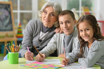 Fototapeta premium Portrait of grandmother with kids drawing at home