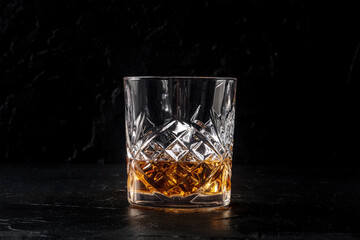 Whiskey in a glass with ice. Bourbon whisky on rocks on a black slate background, a luxury drink, with copy space