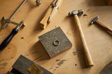 Closeup background image of rustic jewelers workstation with tools and ring on wooden table, copy...