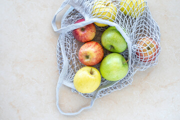 Fresh apples in mesh bag over marble background. 
